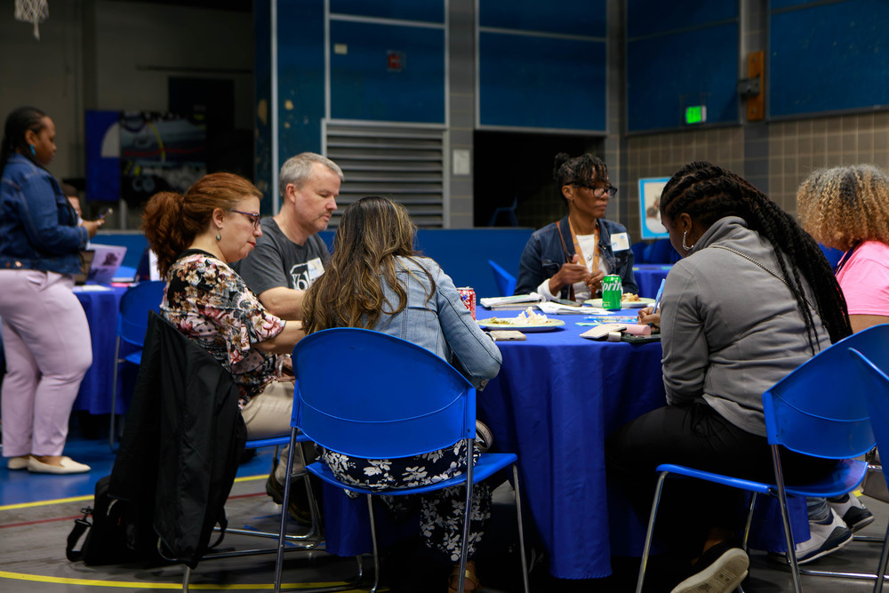 Staff members sit at a table while they do a group exercise.