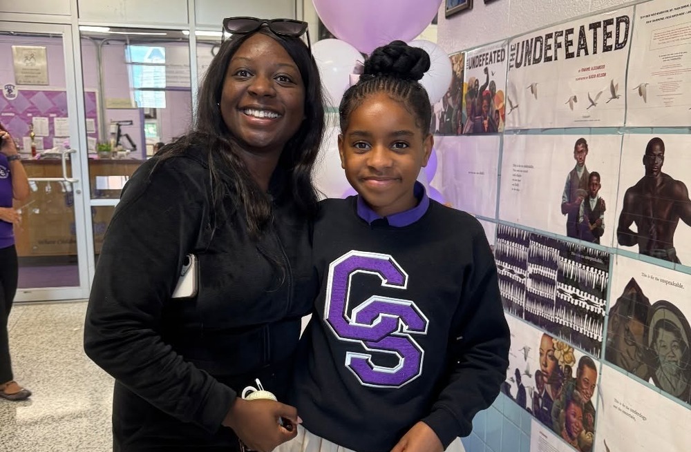 Adult and student posing for photo in the school hallway