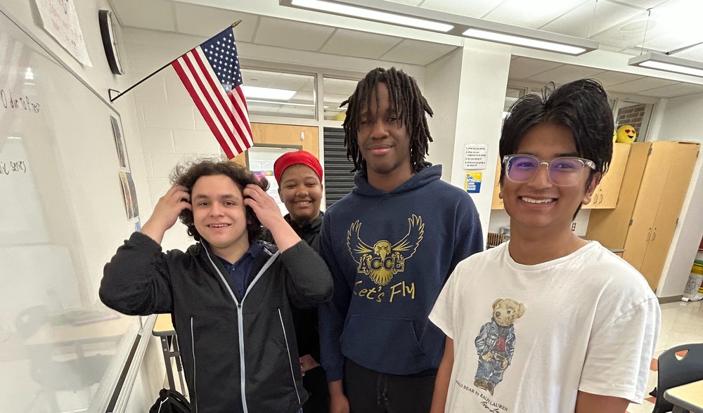 Sudarshan, Jordan, Oscar, and Audrey smile and pose for a photo in a classroom.