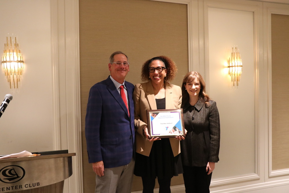 Tina Hike-Hubbard stands next to YMCA Maryland Leadership as she accepts her award. 