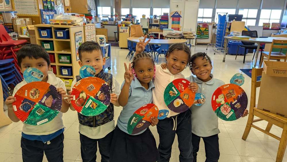 Kindergarten students poses for picture with artwork