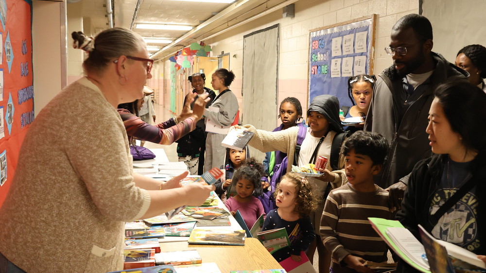Southwest Baltimore Charter CurriculumSpecialist helps hand out books to families
