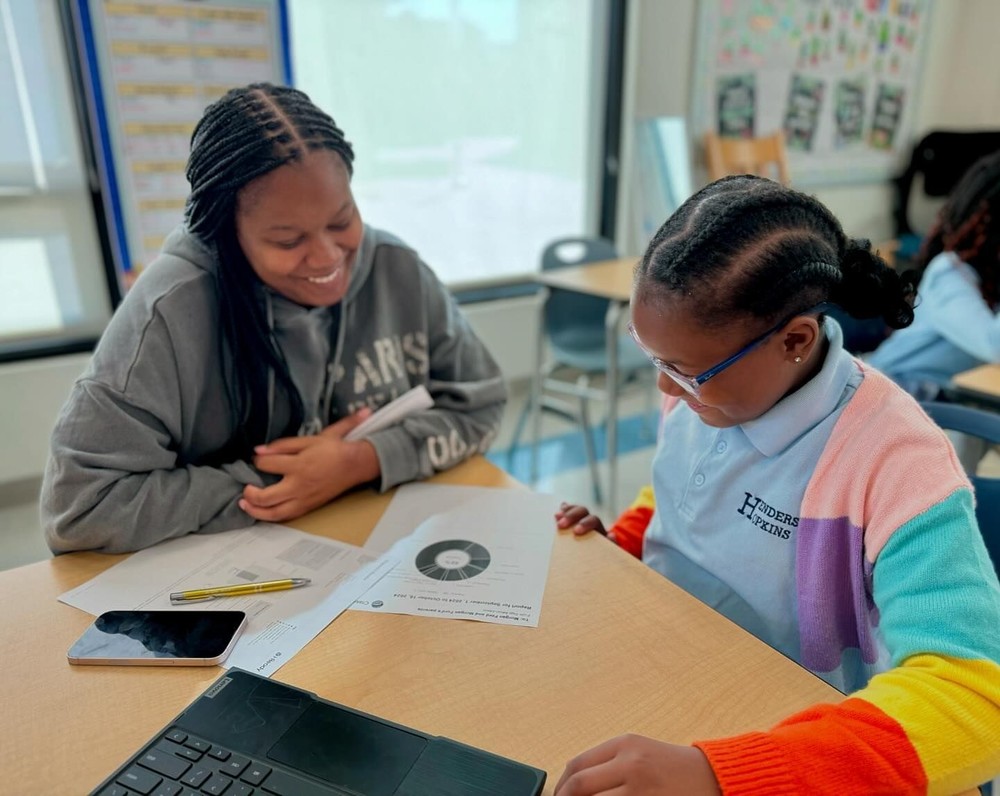 student and teacher working together at a table on a worksheet