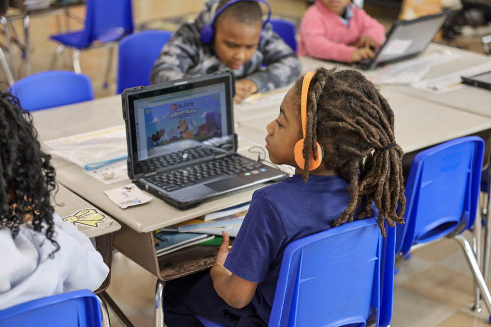 Pre-K student wearing headphones and sitting at a desk with a computer