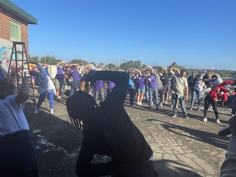 Students and staff stretch before the playground build at Sinclair Elementary.