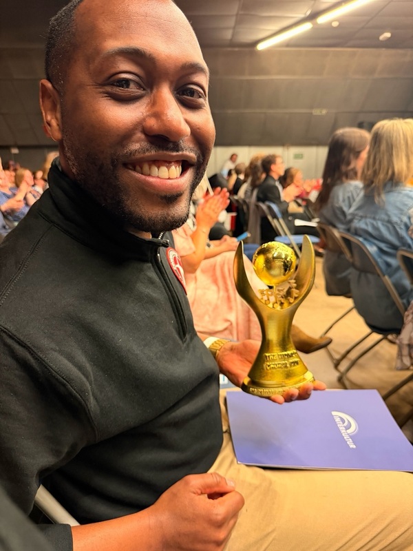 Brandon Booth holding the award from the Sing for Gold competition
