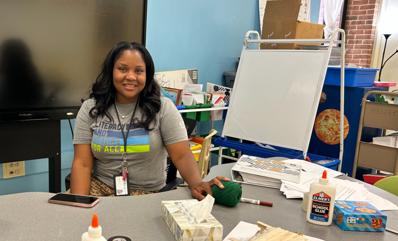 Ms. Cole sits at her desk in her classroom. 