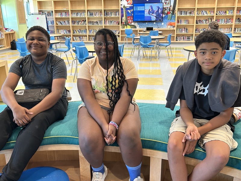 Three participants in the middle school explorations program pose for a picture in the library. 