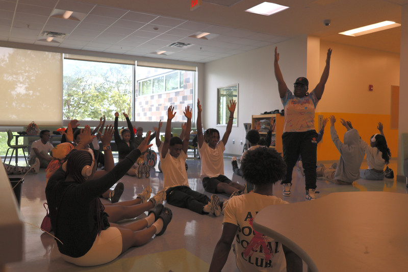 A cam instructor leads students through a stretching exercise at fine arts camp.