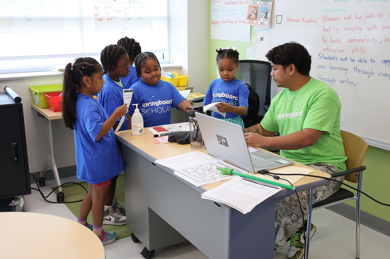 Teachers helps students at their desk. 