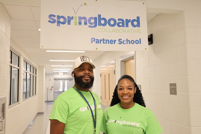 Program manager Ms. Gilliam poses with another staff member under the 'springboard partner school' sign. 