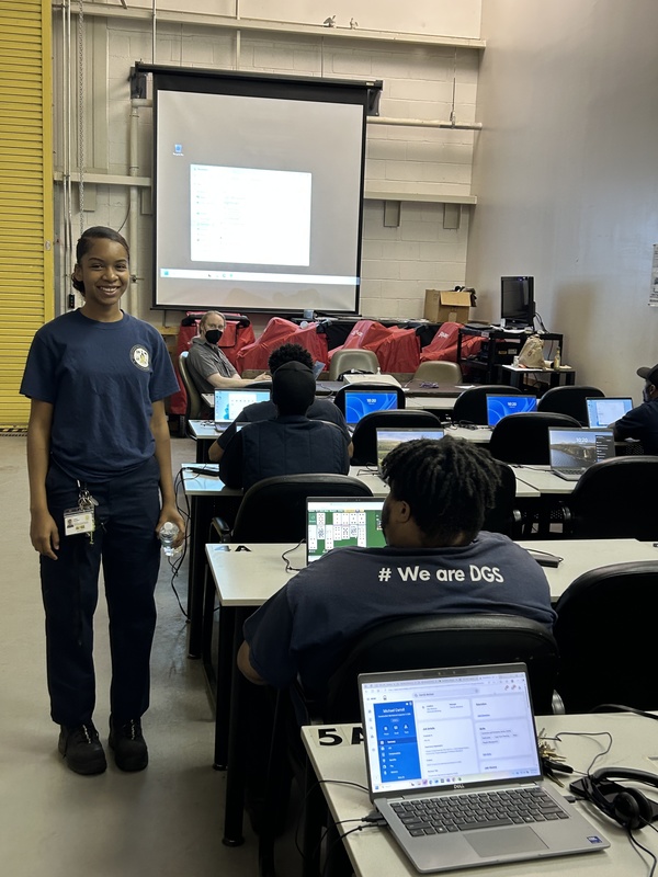 Celina stands by a classroom full of colleagues taking training