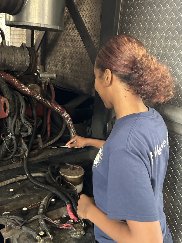 Celina works on a car at her mechanic shop.