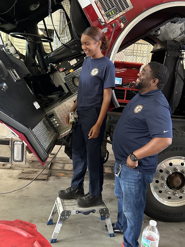 Celina, pictured left and Antwan pictured right, stand by a fire truck they are fixing. 