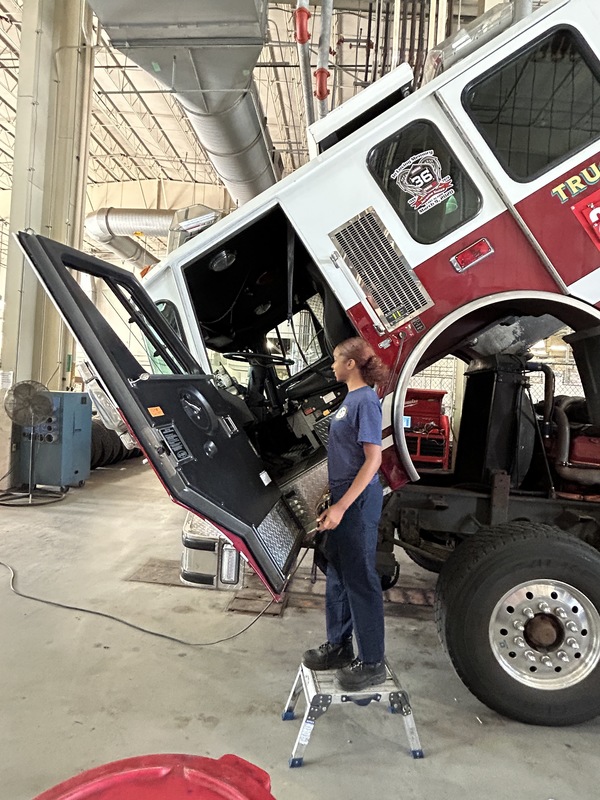 Celina works on a car at her mechanic shop.