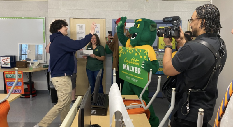Malver accept his scholarship and celebrates with school officials while being recorded by City Schools video team.