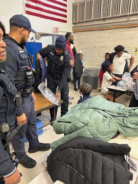 School Police hand out coats and pose for photos at Midtown Academy.
