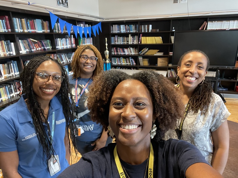 Kirred Marcano-Briscoe poses with Tanipa Thomas and other City Schools Mentors during a session in a school's library.