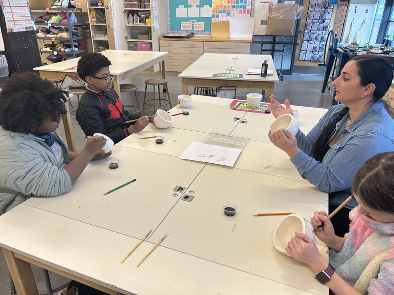 art teacher Stephanie Cafaro-Edwards with three students working on their tea bowls in a classroom setting