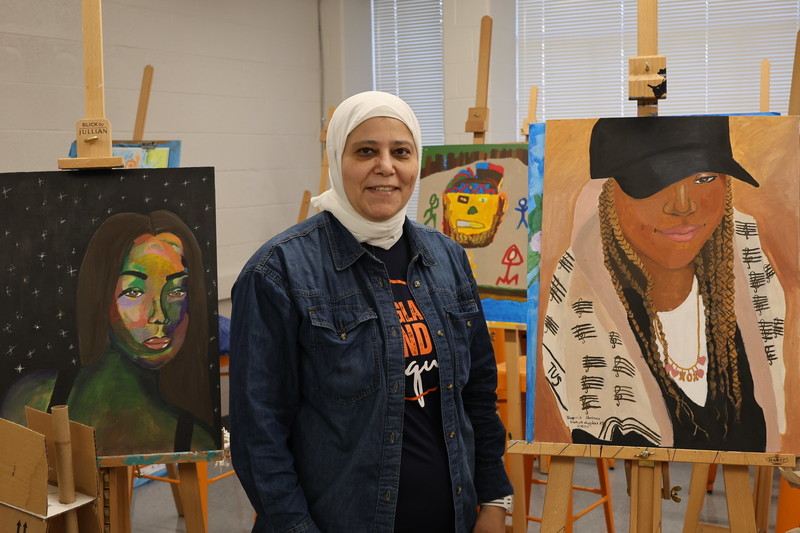 Ms. Hussain stands next to some of her favorite student art pieces.