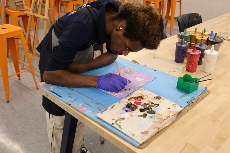 Art student finishes their painting by hand during class.