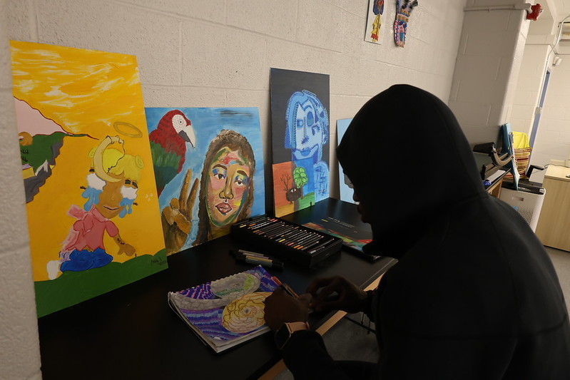 Art student finishes their painting by hand during class.