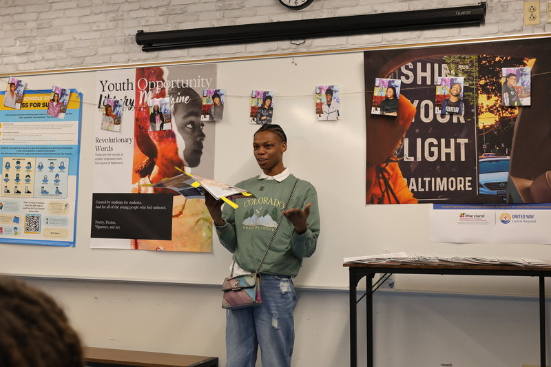 Student reading a book in front of the class