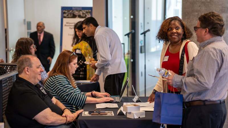 MWBE symposium attendees chat over a table