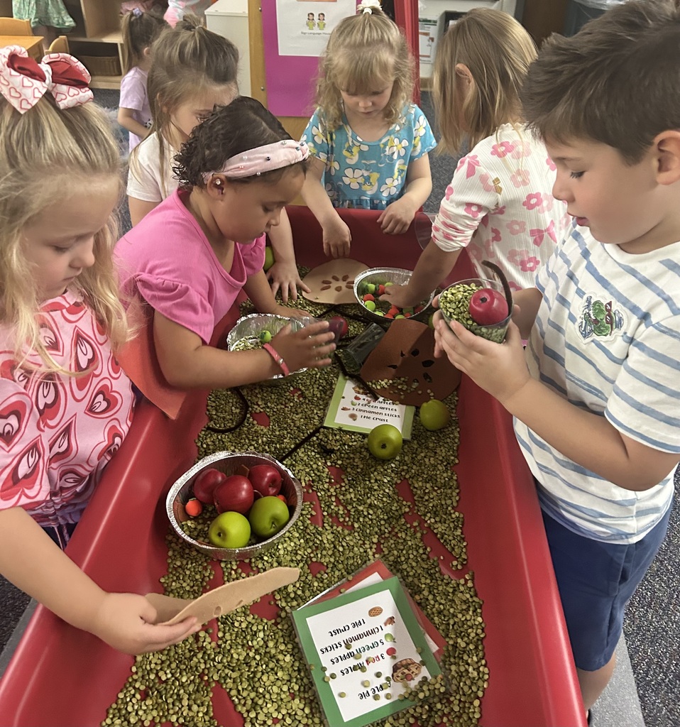 Students playing in sensory table pretending to make apple pie