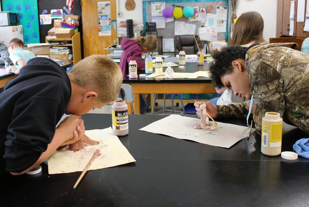 Students holding art projects