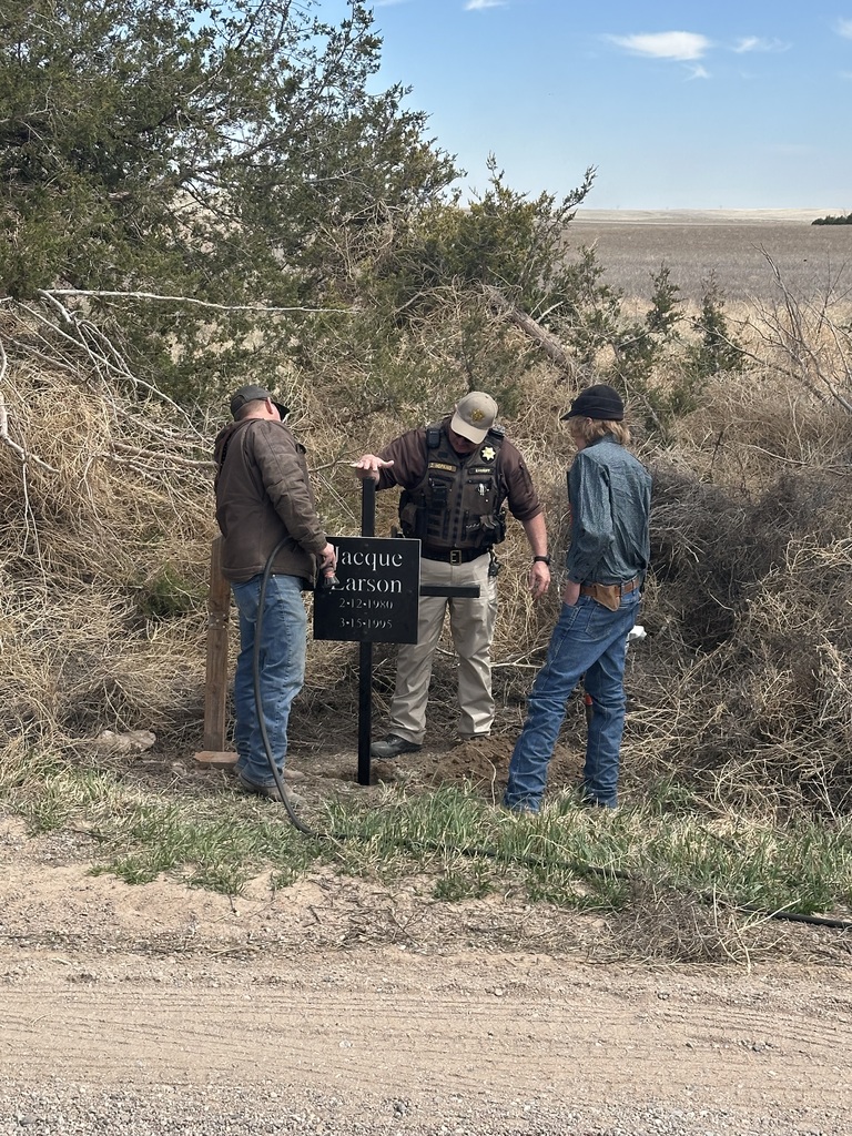 Student a Sherriff standing by a memorial 