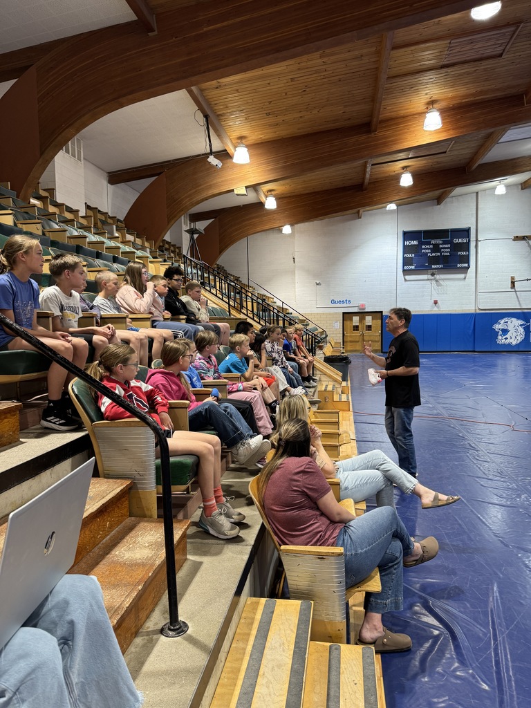 Students sitting in the bleachers listening to a speaker 