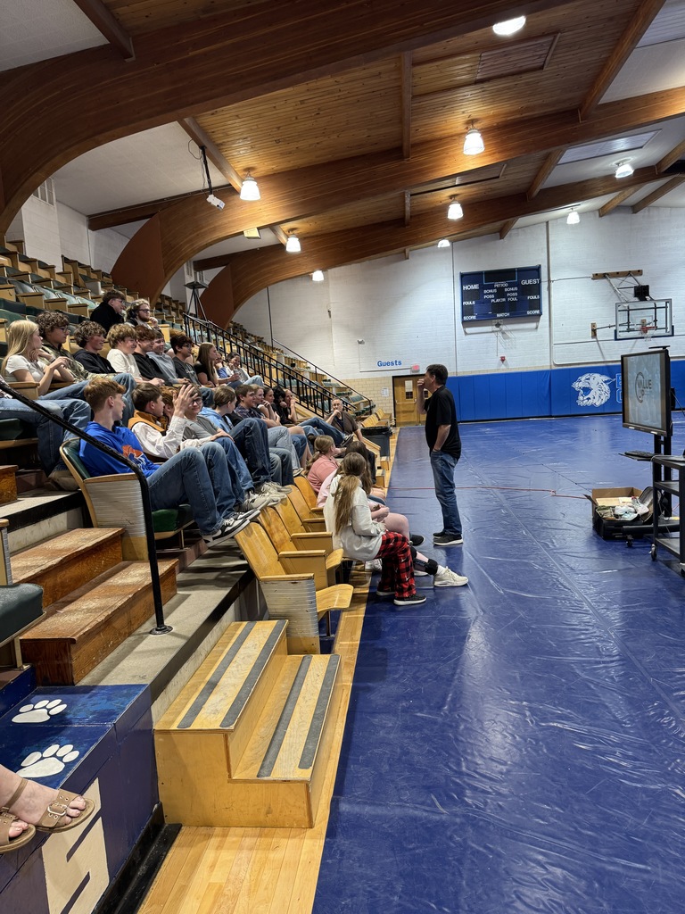 Students sitting in the bleachers listening to a speaker 