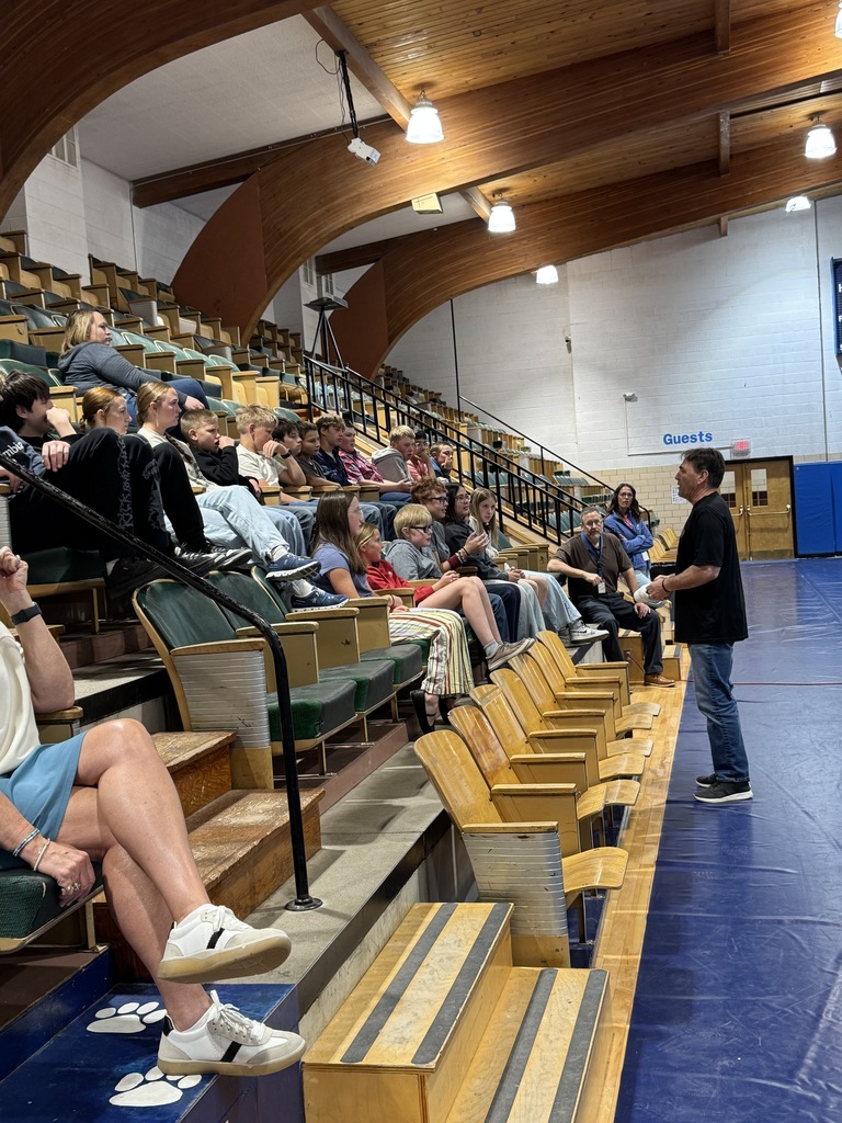 Students sitting in the bleachers listening to a speaker 