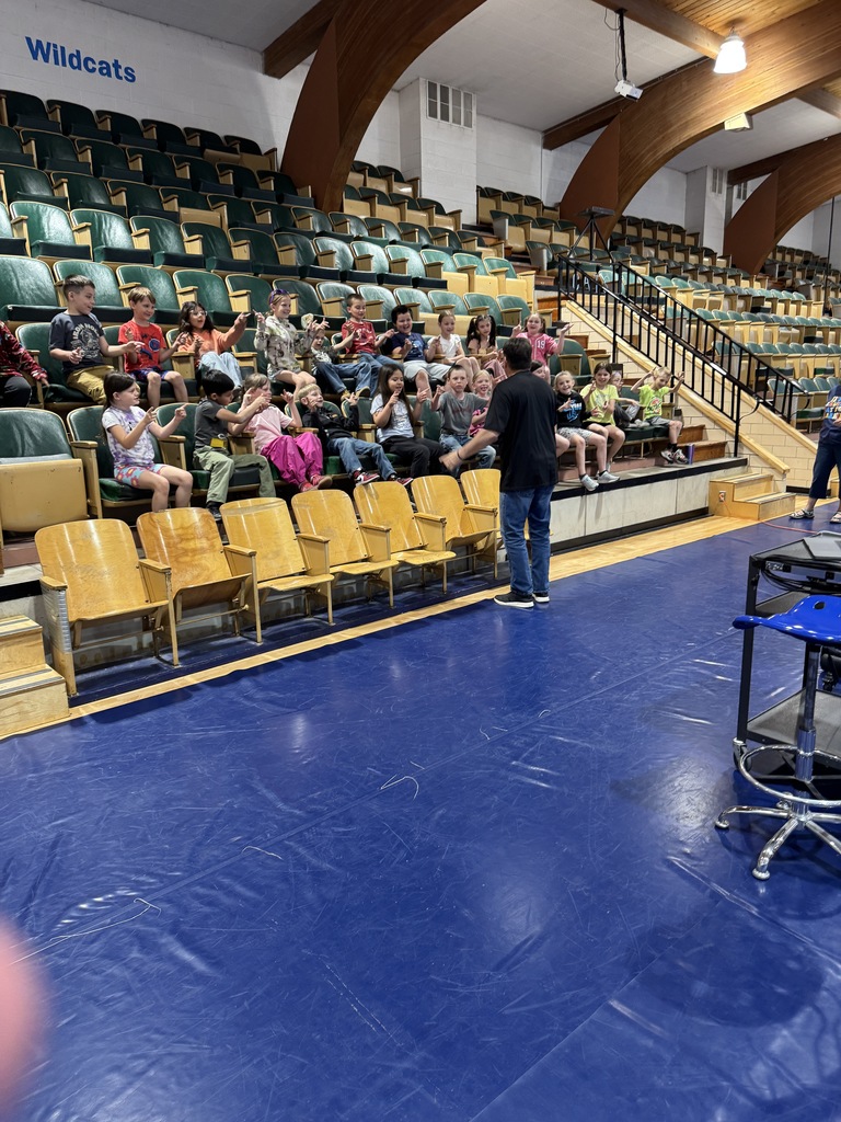Students sitting in the bleachers listening to a speaker 