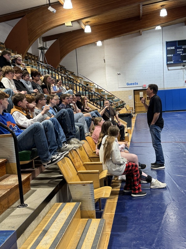 Students sitting in the bleachers listening to a speaker 