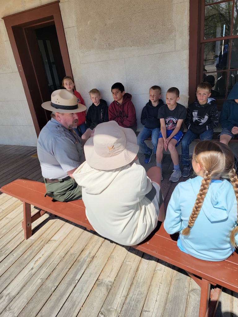 A series of photos showing Banner County students on a field trip to a historical museum or general store. Students are seen exploring vintage displays, looking at historical artifacts on wooden shelves, and gathered together in a rustic, wood-paneled building.
