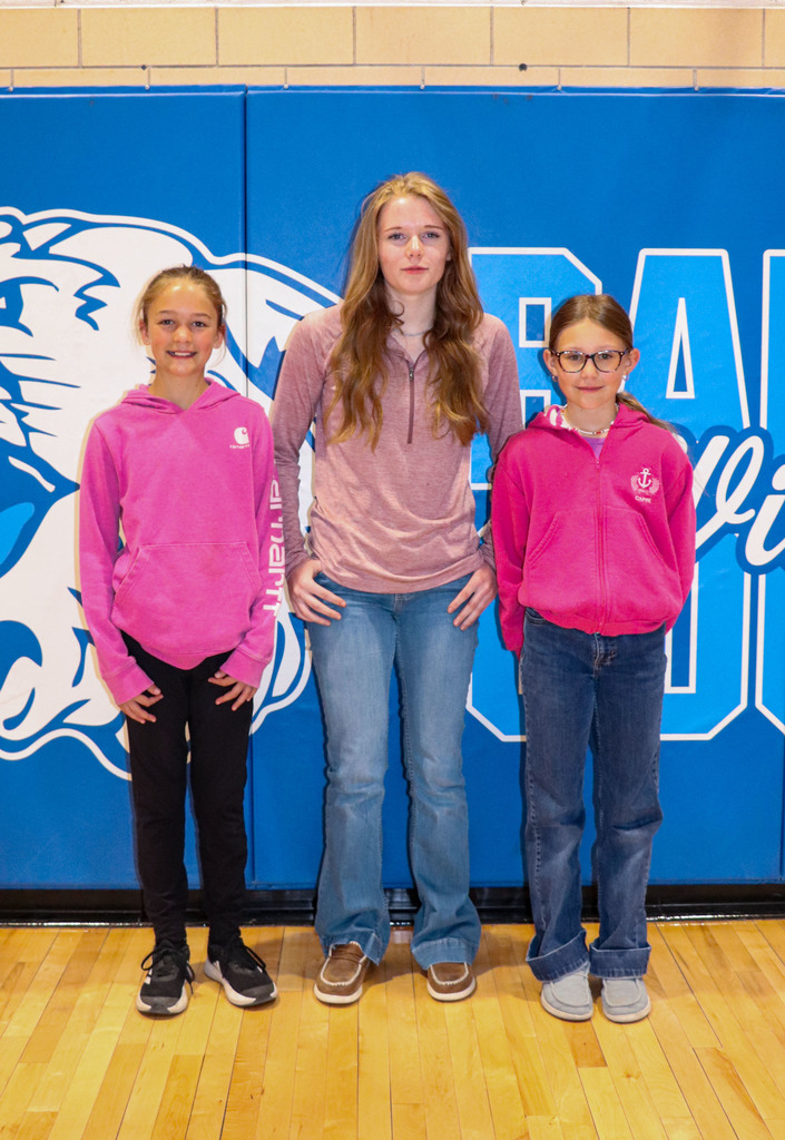 Three students standing in the gym after being recognized as students of the month.