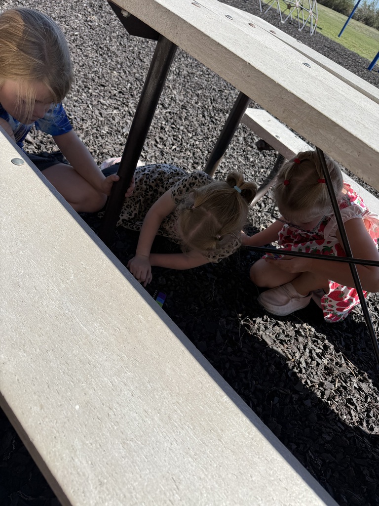 3 students looking under a table