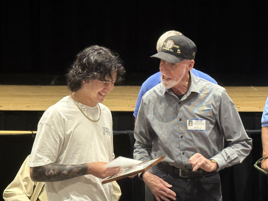 A member of the VFW giving Jake his award and check. 