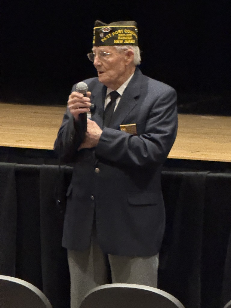 One member of the VFW speaking to the students through the microphone. 