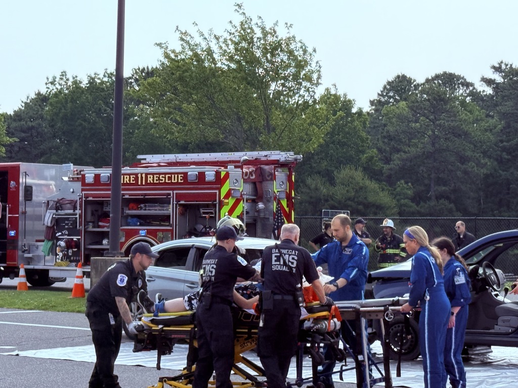 Image of another extricated student being transferred from an EMS stretcher to the helicopter stretcher as an EMS member is performing CPR on the student. 
