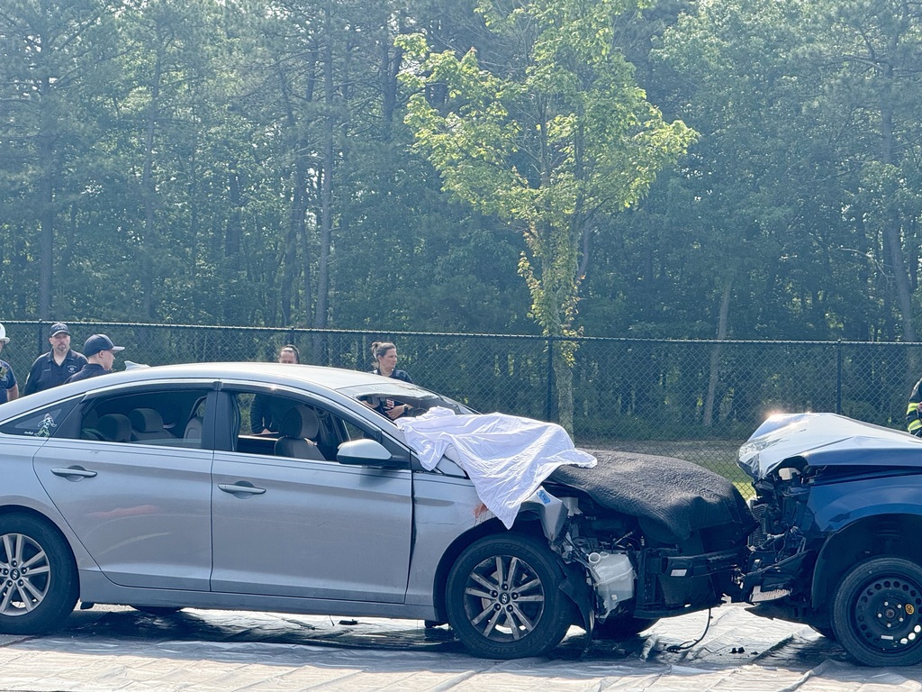 Image of the two cars in the accident with a white cloth covering the student who went through the windshield. 