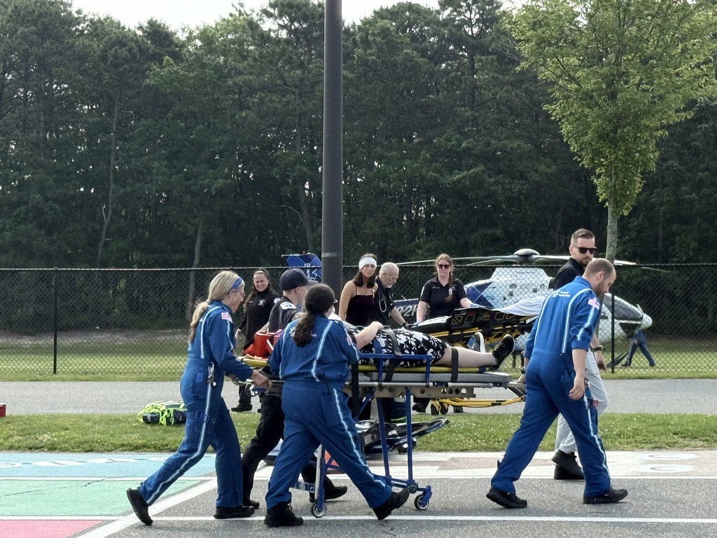 Helicopter EMS team transporting the student on the stretcher to the chopper while an EMS member continues to perform CPR. 