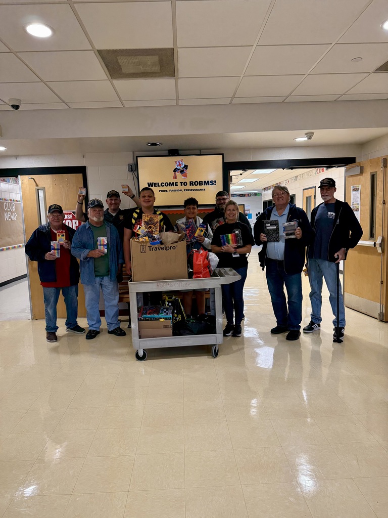 Image of members of the VFW, students, and district personnel with the donations on a cart. 