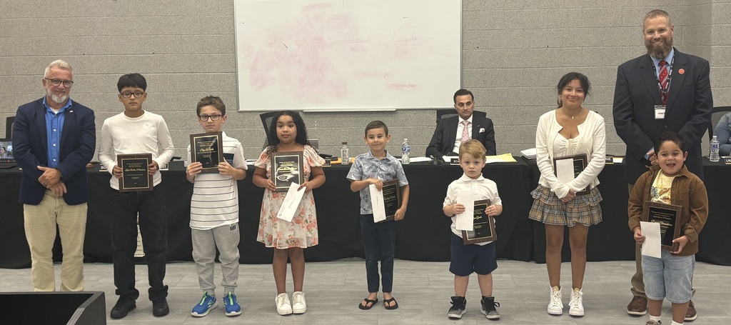 Image of the September UPstanders posing with the Superintendent and Board President holding their plaques. 
