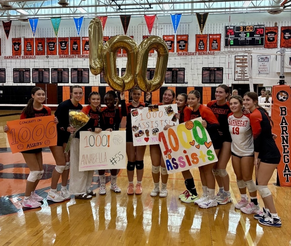 Image of Annabella surrounded by her teammates who are holding signs and balloons.