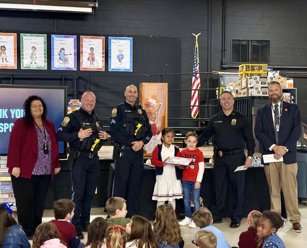 Image of the Superintendent, Principal, three police officers, and two students presenting the handmade cards and check.
