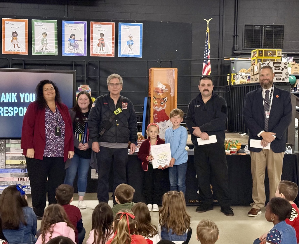 Image of the Superintendent, Principal, teacher, two fire fighters, and two students presenting the handmade cards and check.