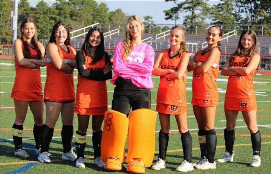 Image of Jadeyn in her goalie gear surrounded by her teammates.